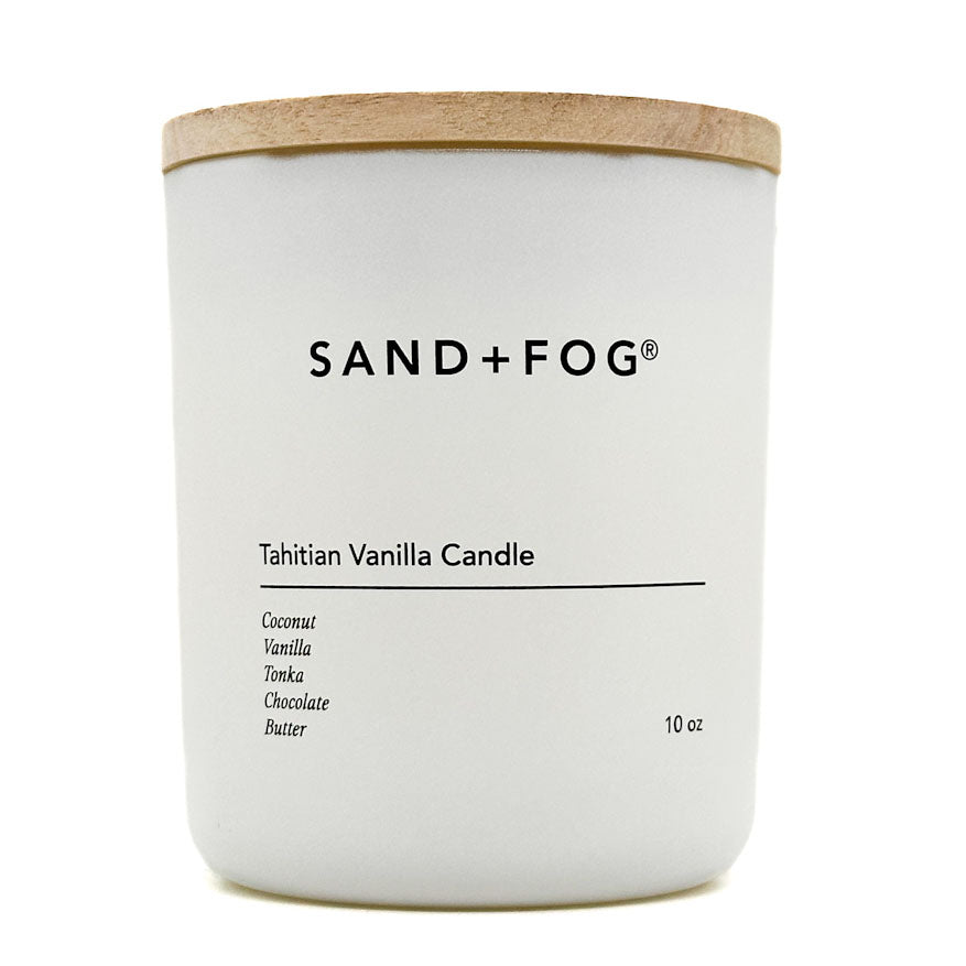 White candle with a wooden lid labeled 'SAND + FOG Tahitian Vanilla Candle' on a white background