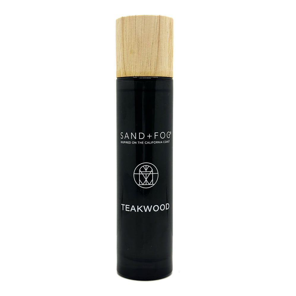 Black bottle with wooden cap labeled 'Sand + Fog Teakwood' on a white background