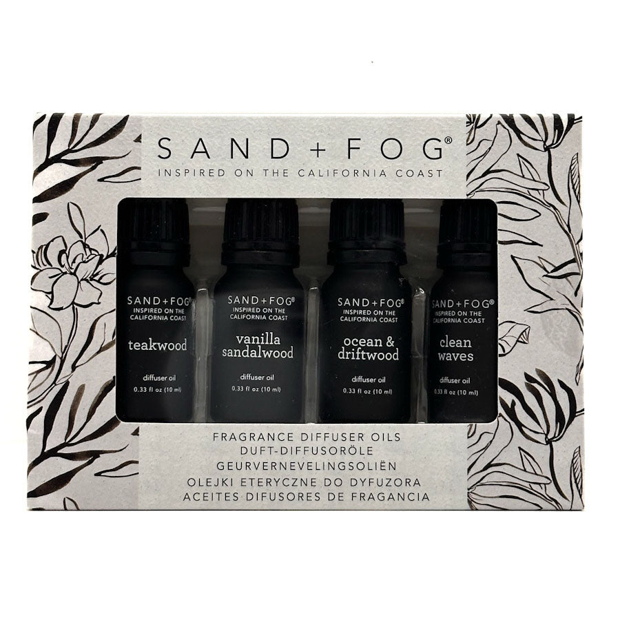 Sand + Fog Inspired on the California Coast fragrance diffuser oils set in its original packaging, featuring four black bottles with black caps: teakwood, vanilla sandalwood, ocean & driftwood, and clean waves.