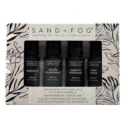 Sand + Fog Inspired on the California Coast fragrance diffuser oils set in its original packaging, featuring four black bottles with black caps: teakwood, vanilla sandalwood, ocean & driftwood, and clean waves.