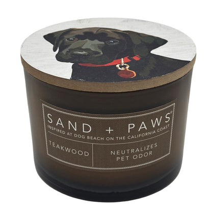 Teakwood candle with a dog illustration on the lid and 'Sand + Paws' branding.