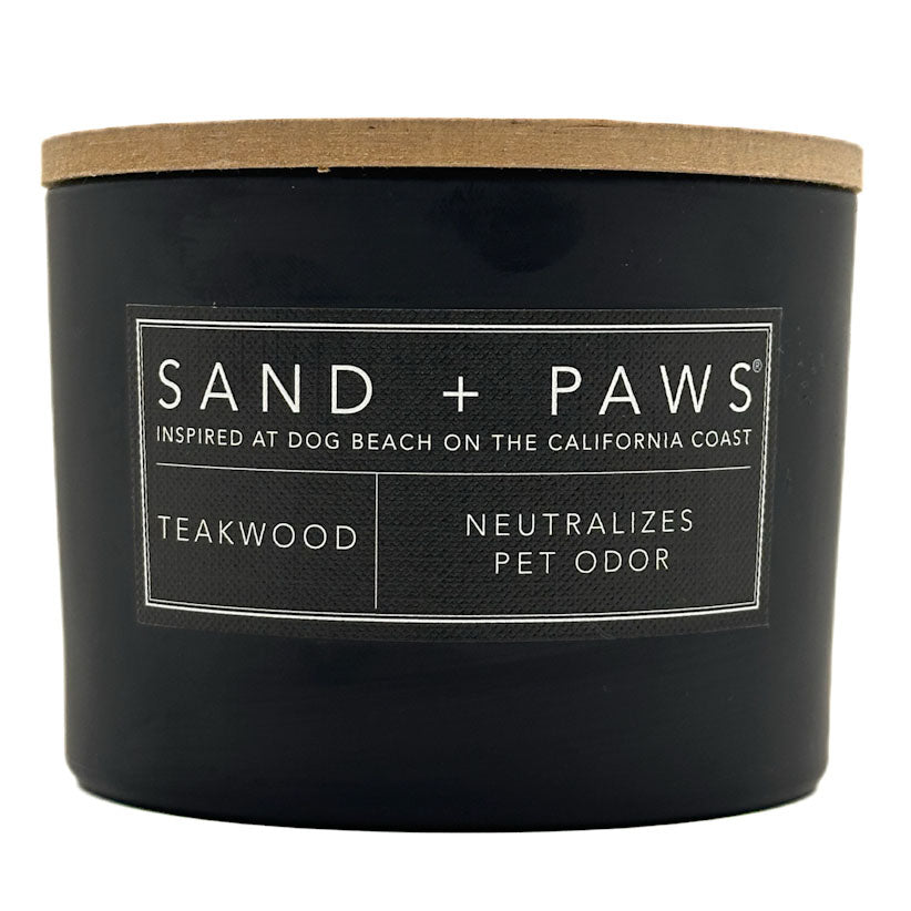 Teakwood Black candle with a wooden lid labeled 'Sand + Paws' on a white background
