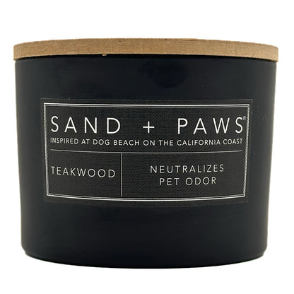 Teakwood Black candle with a wooden lid labeled 'Sand + Paws' on a white background
