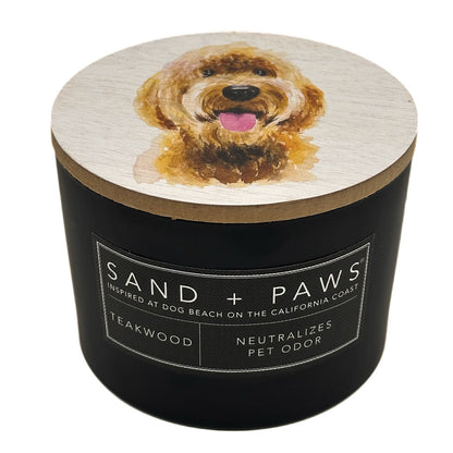 Teakwood Candle with a dog illustration on the lid and 'Sand + Paws' branding.