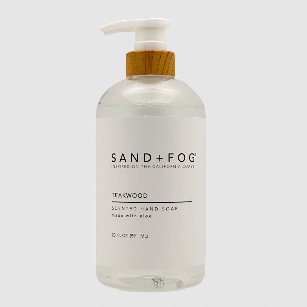 Clear SAND + FOG Teakwood hand soap bottle with pump and wooden top on a light grey background
