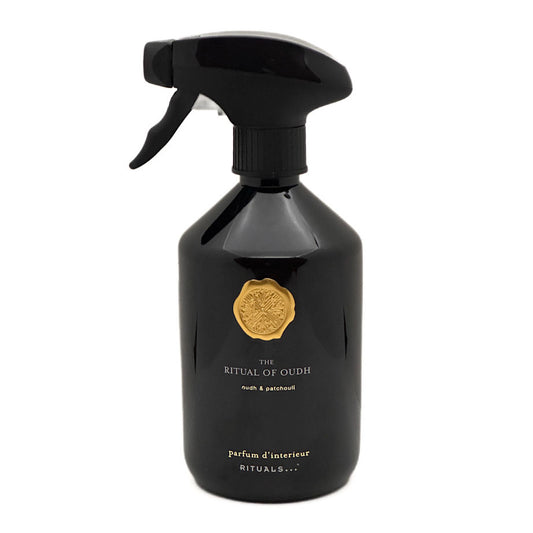 A glossy black spray bottle with a trigger sprayer, featuring a gold crest emblem and white text reading 'THE RITUAL OF OUDH' and 'Perfum d'intérieur RITUALS.
