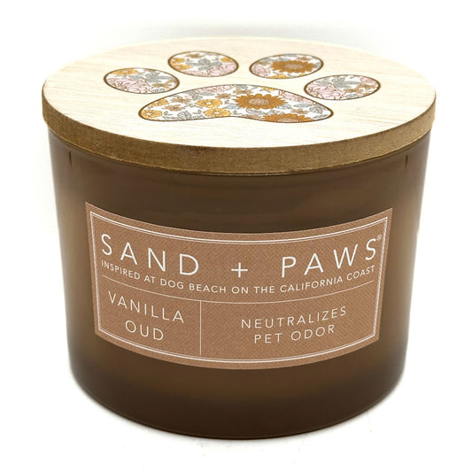 Vanilla Oud candle with 'Sand + Paws' branding on a white background