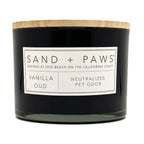Vanilla Oud Black candle with a wooden lid labeled 'Sand + Paws' on a white background