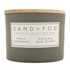 Gray Vanilla Sandalwood candle with a wooden lid and 'Sand + Fog' label on a white background
