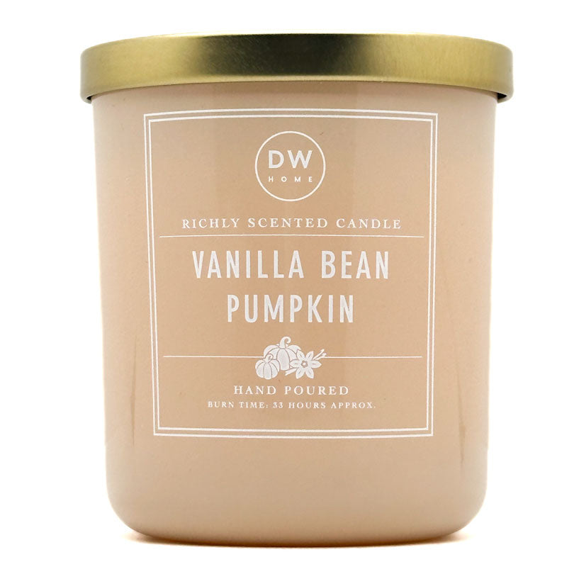 A DW Home Vanilla Bean Pumpkin scented candle in a matte beige jar with a metallic gold lid and a white label.