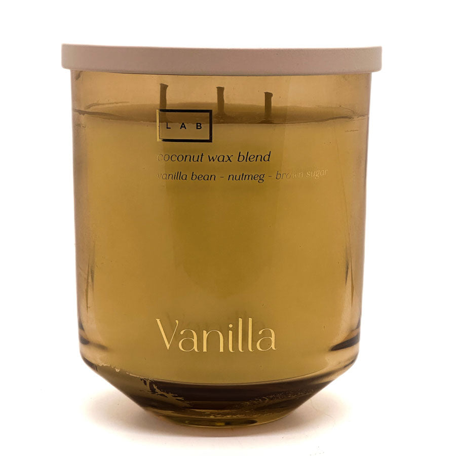 A LAB brand vanilla scented candle in a translucent amber glass jar with a light beige lid, on a white background.