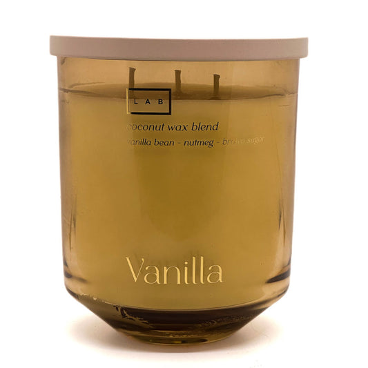 A LAB brand vanilla scented candle in a translucent amber glass jar with a light beige lid, on a white background.