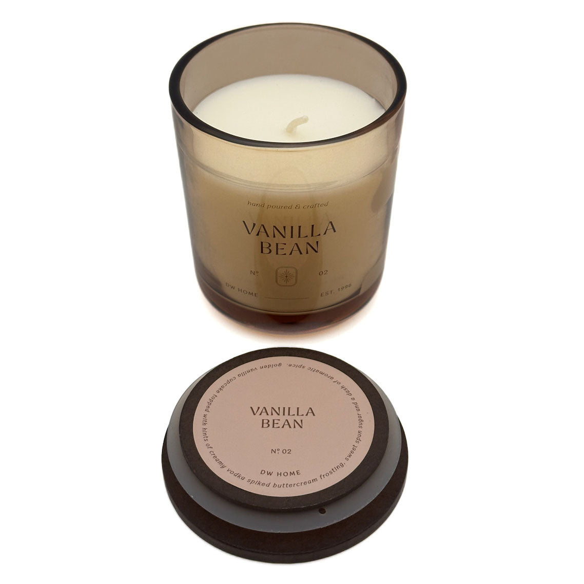 A DW Home jar candle labeled 'VANILLA BEAN' with white wax in a translucent smoky amber glass container, shown with its dark lid placed below on a white background.
