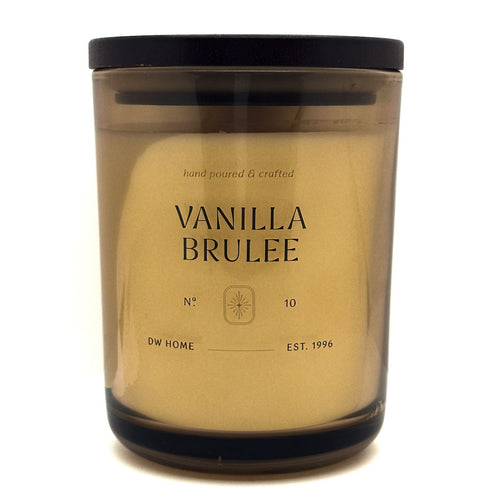 DW Home Vanilla Brulee candle in a clear container with a black lid on a white background