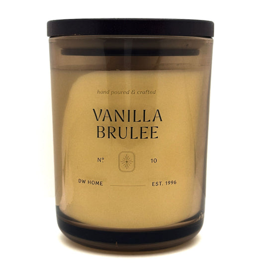 DW Home Vanilla Brulee candle in a clear container with a black lid on a white background