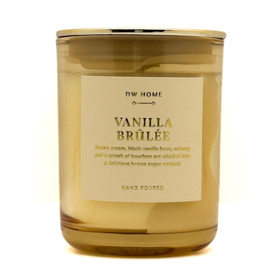 A glass jar Mini candle with a gold-toned lid and a cream-colored label reading 'DW HOME VANILLA BRÜLÉE'. The candle is photographed on a clean white background.