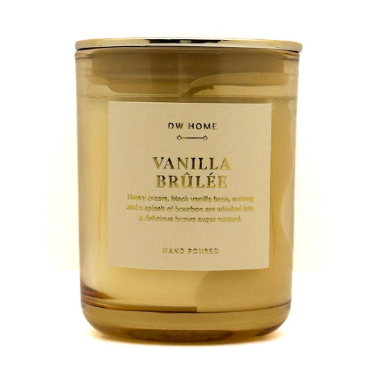 A glass jar Mini candle with a gold-toned lid and a cream-colored label reading 'DW HOME VANILLA BRÜLÉE'. The candle is photographed on a clean white background.