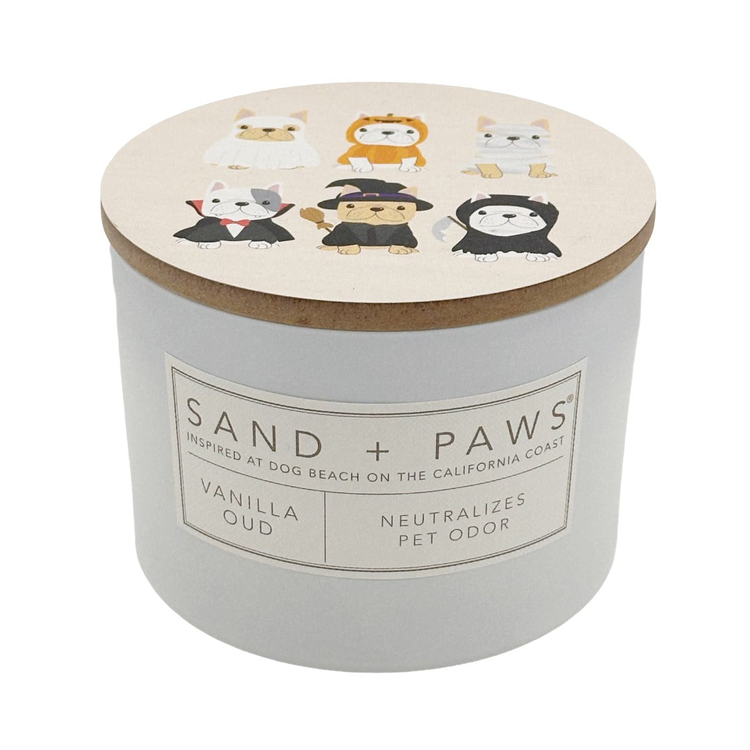 A pet odour neutralising candle in a white cylindrical jar with a light wood lid. The lid features cartoon illustrations of six dogs in different outfits.