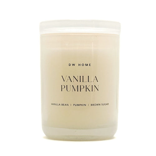 A frosted glass jar candle with creamy off-white wax, featuring a white lid and black text that reads 'DW HOME VANILLA PUMPKIN' on the front label.