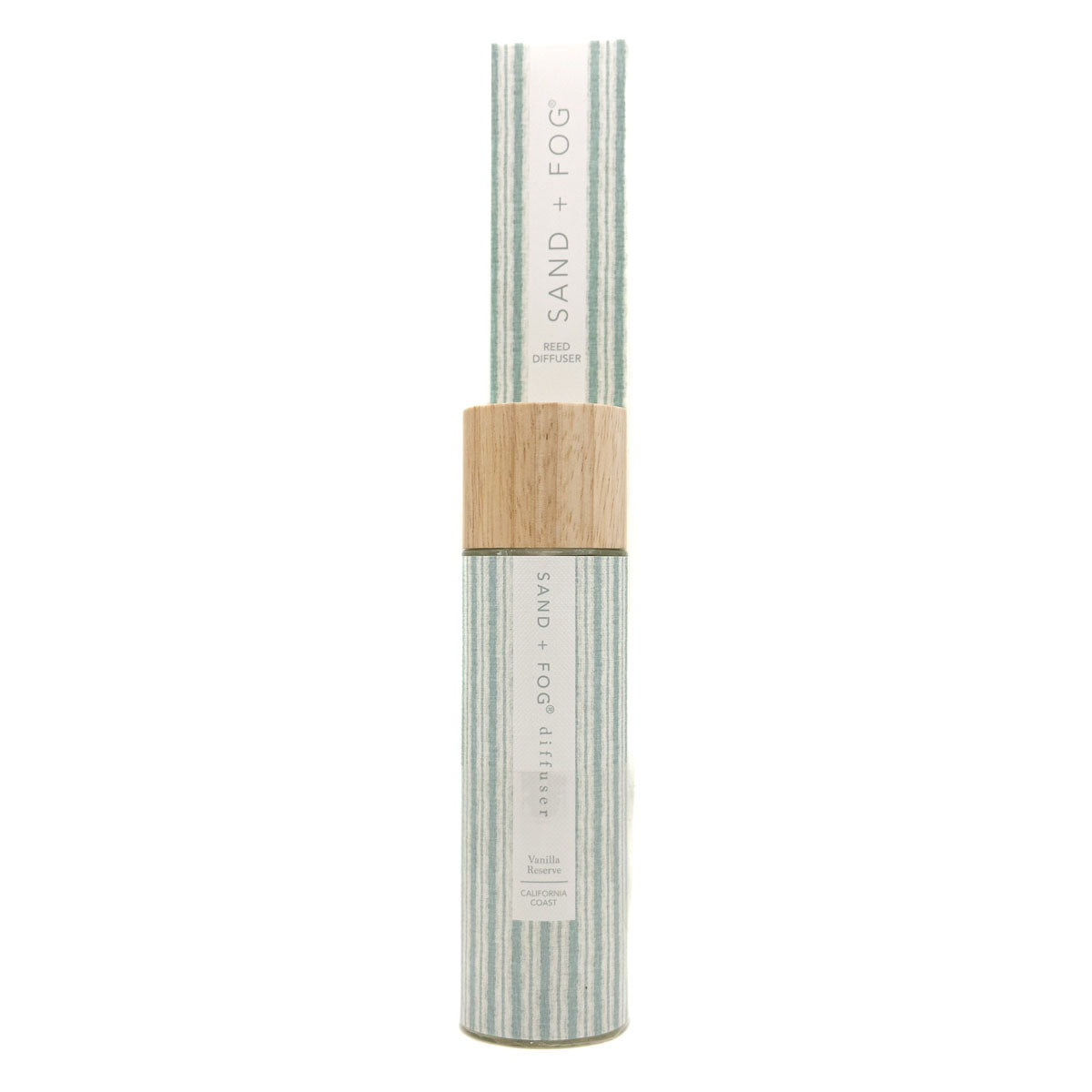 A cylindrical bottle of Vanilla Reserve Sand + Fog reed diffuer with a light wood cap, set against a plain white background.