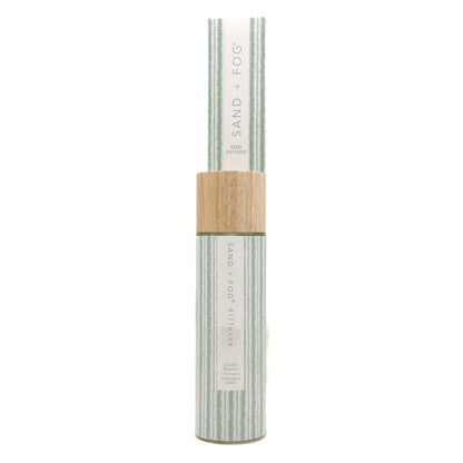 A cylindrical bottle of Vanilla Reserve Sand + Fog reed diffuer with a light wood cap, set against a plain white background.