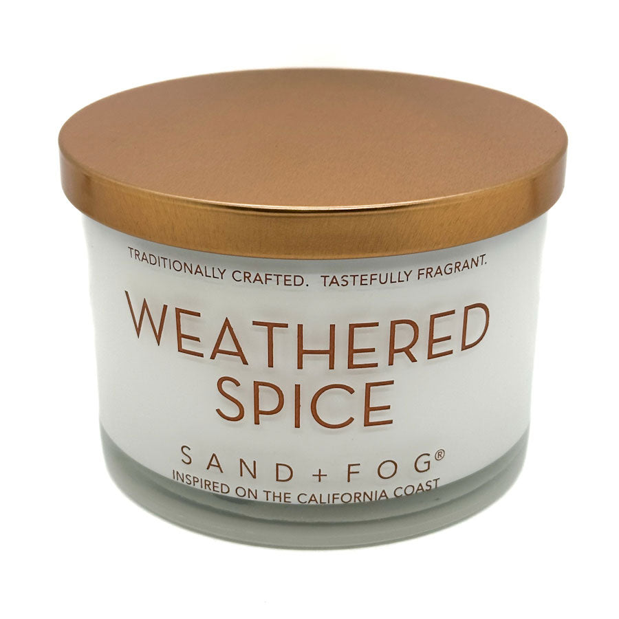 Candle labeled 'Weathered Spice' by Sand + Fog on a white background