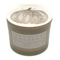 Green candle with a label for 'White Pumpkin' by Sand + Fog on a white background