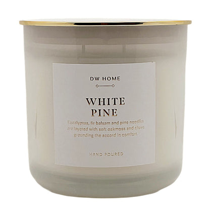 A white soy wax candle in a frosted glass jar with a gold metallic rim and a white label that reads 'DW HOME WHITE PINE'.