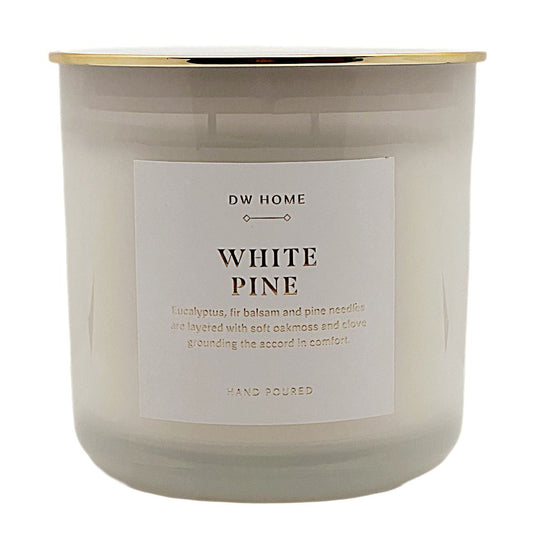 A white soy wax candle in a frosted glass jar with a gold metallic rim and a white label that reads 'DW HOME WHITE PINE'.