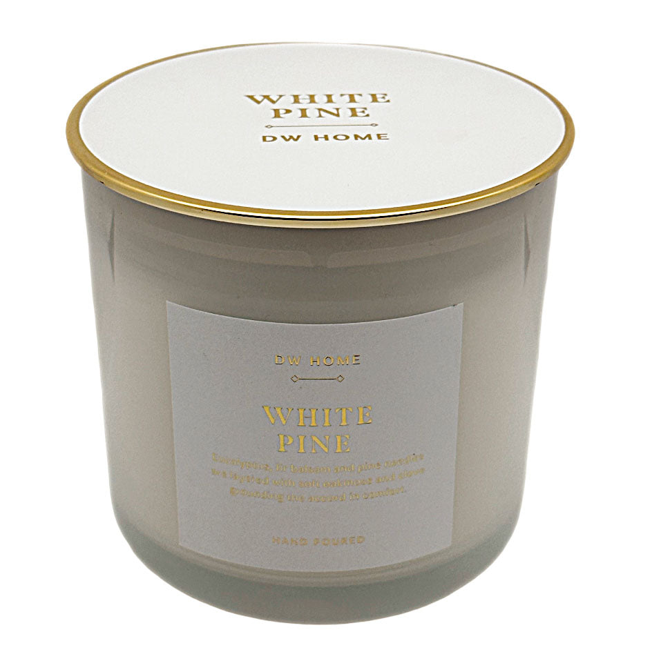 A DW Home White Pine scented candle in a frosted glass jar with a white lid and gold trim, featuring a white label with gold lettering.